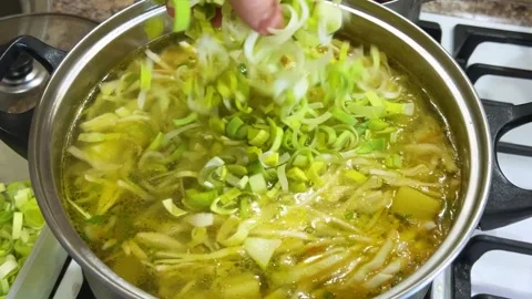 Adding chopped leek stems to a pot with potatoes, carrots and cabbage.  库存影片 302754764