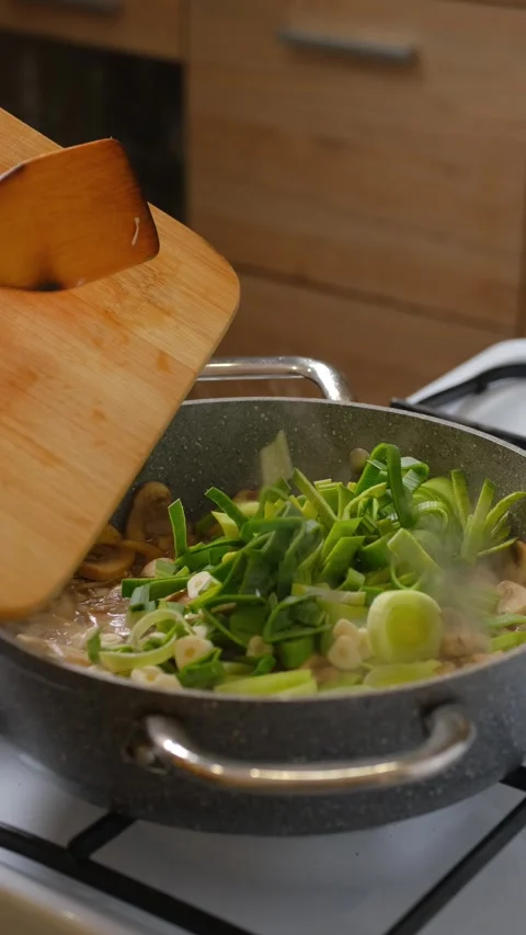 Adding chopped leeks and garlic to the frying pan with mushrooms Stock Footage 321680493