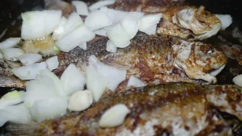 Adding chopped onion to the pan where the fish is fried Stock-Footage 224884713