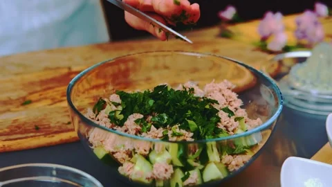 Adding chopped parsley to una and cucumber salad Видео 252244829