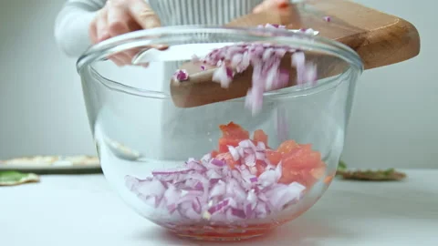 Adding chopped red onion into a transparent glass bowl with plum tomatoes in 4K. Stock Footage 142822962