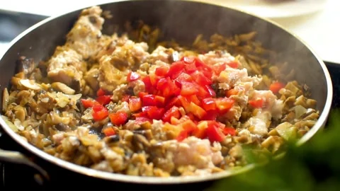 Adding chopped red peppers to meat in a skillet Video stock 333833928