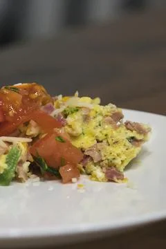 Adding chopped red tomatoes on top of an omelet Stock Photos