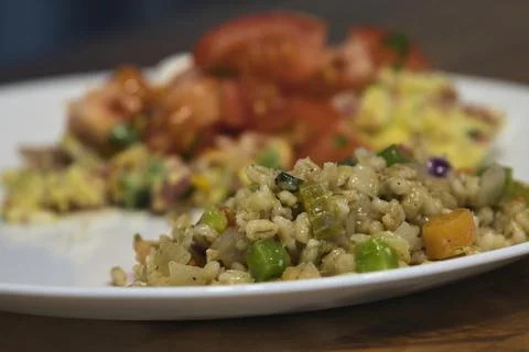 Adding chopped red tomatoes on top of an omelet Stock Photos
