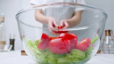Adding chopped Tomatoes, Cucumber, Red onion, Green Bell Pepper in a Greek Salad 142114207