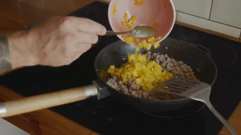 Adding chopped yellow bell pepper to fried minced meat in pan Video stock 315243341