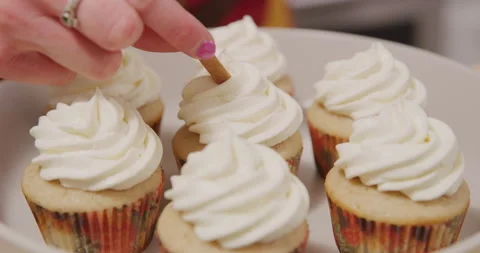 Adding cinnamon stick decoration to cupcakes on plate Stock Footage 249371096