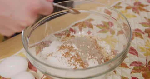 Adding cloves spice powder to mixing bowl dry mix Stock Footage 249314060
