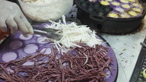 Adding Coconut and Sweet Filling to Purple Pancake Batter on Street Food Griddle Video stock 327841641