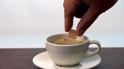 Adding coffee with 3 organic sugar cubes in ceramic cup on wooden table Stock Footage 317110510