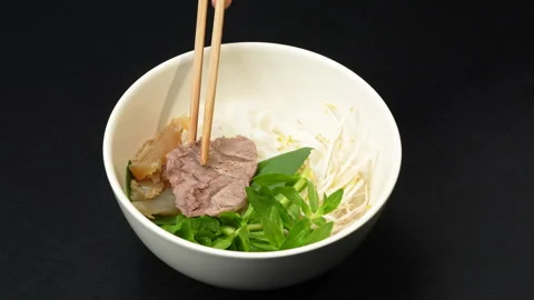 Adding Cooked Beef Slices and Tendon into Vietnamese Pho Bowl 動画素材 339653804