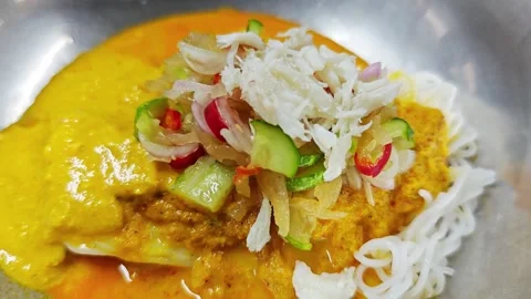 Adding crab meat topping on Thai rice noodles with curry. Stock Footage 342515798