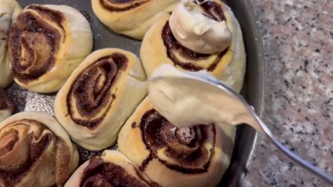 Adding Cream Cheese Frosting to Cinnamon Rolls in a Baking Pan Stock Footage 345522454