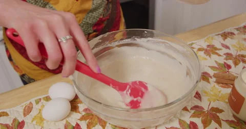 Adding cream into mix in mixing bowl and mixing with spatula Video stock 249352468