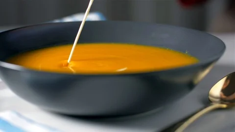 Adding cream to pumpkin soup cream. Slow motion Video stock 105878013
