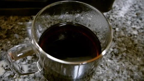 Adding a creamer into a cup of coffee and mixing with a tea spoon Stock Footage 96048666