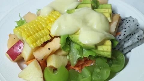 Adding creamy dressing with a spoon onto fresh fruit salad. Stock Footage 345293029