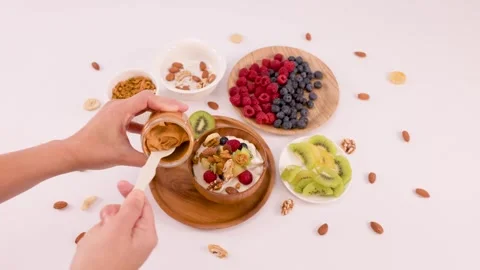 Adding Creamy Peanut Butter to a Healthy Yogurt Breakfast Bowl Stock Footage 337770840