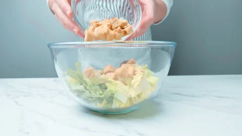 Adding croutons into a Caesar Salad in a transparent glass bowl in 4K. Stock Footage 140768603