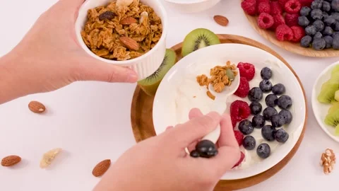 Adding Crunchy Granola to a Fresh Greek Yogurt Fruit Bowl Stock Footage 337877142