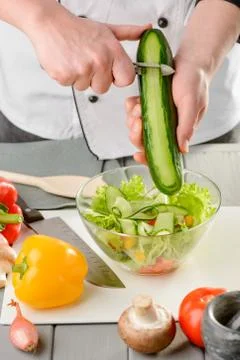 Adding cucumber ribbons to the vegetable salad Stock Photos