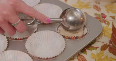 Adding cupcake mix into tray and wrapper with scoop closeup Video stock 249352059