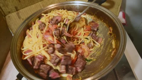 Adding Diced Beef to Pasta with Tomato Sauce During Final Cooking Process Stock Footage 340956173