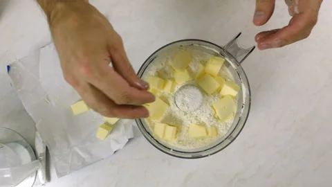 Adding diced butter into food processor cup with flour Stock Footage 97969503