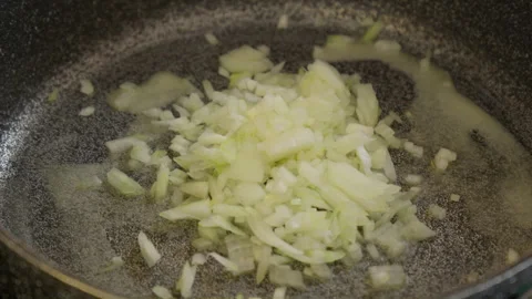 Adding diced onion on melted butter in gray frying pan skillet Vídeo Stock 266782043