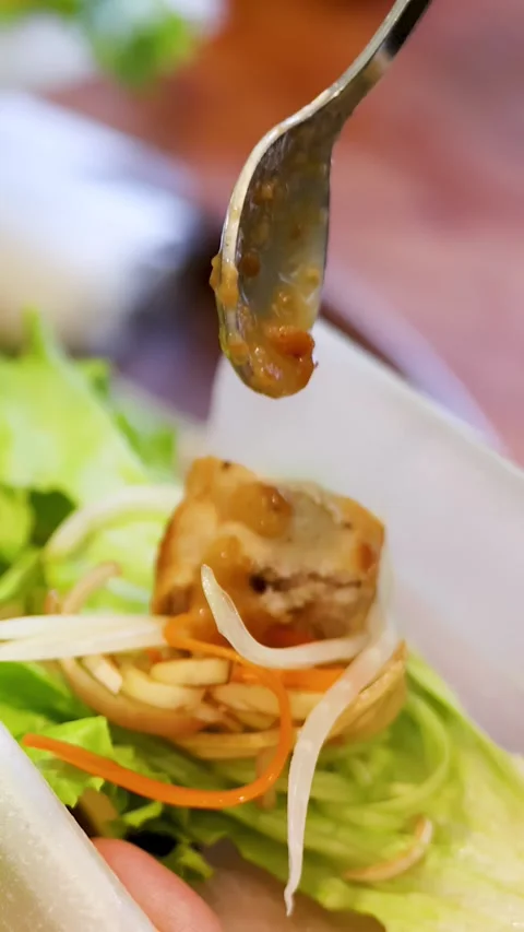 Adding Dipping Sauce to Vietnamese Nem Nuong Spring Roll with Spoon Stock Footage 334920596