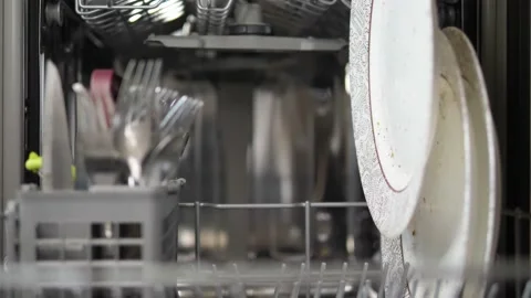 Adding dirty dishes into the dishwasher machine Stock Footage 169769834