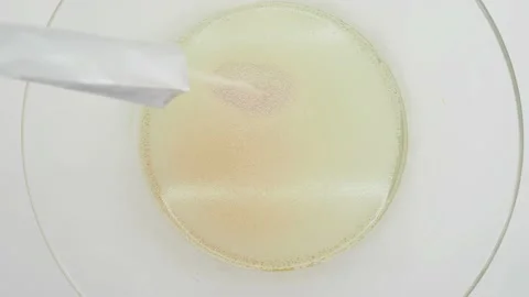 Adding Dried Yeast Granules Into A Transparent Bowl Containing Water, UK 動画素材 138345425