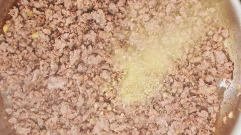 Adding dry oregano to mince meat in a frying pan. Stock Footage 154940061