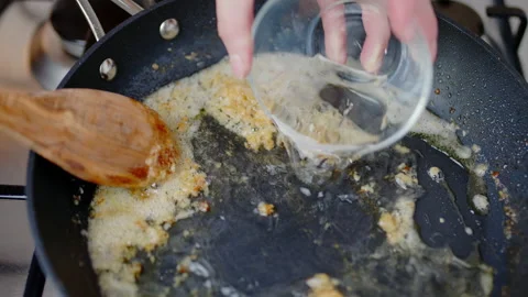 Adding dry white wine into a preheated pan, and frying with melted cream in 4K. Stock Footage 138065779