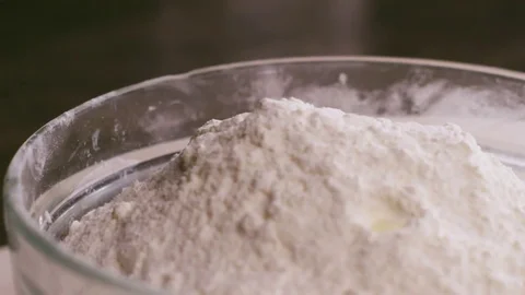 Adding an egg to a bowl with flour Stock Footage 75893806