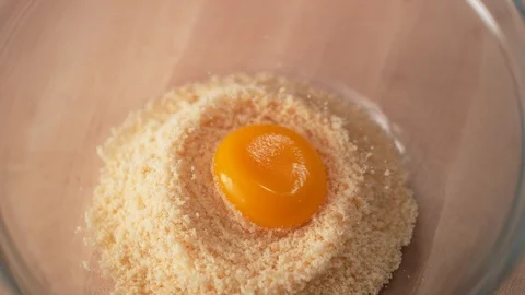 Adding egg into bread crumb in a bowl. Slow Motion. Video stock 104456263