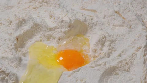 Adding egg to flour, baker in bowl. Close up shot of pouring egg in well mound Video stock 271294659