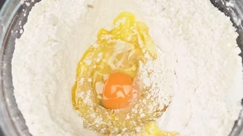 Adding egg to the mixture. Process of making dough. Vídeos de archivo 151046702