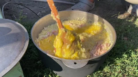 Adding Eggs and Stirring Porridge with Canned Meat Outdoor Stock Footage 314191935