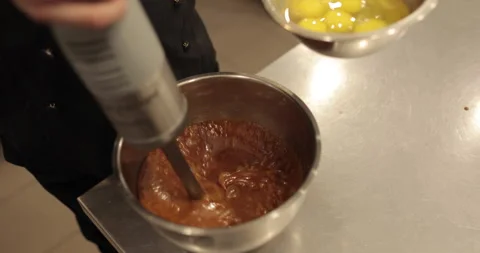Adding the eggs to the bowl while the immersion blender is running. Stock Footage 256409176