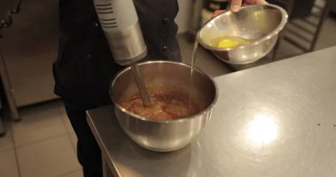Adding the eggs to the bowl while the immersion blender is running. Stock Footage 256409463