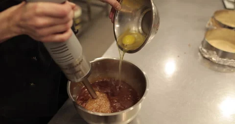 Adding the eggs to the bowl while the immersion blender is running. Stock Footage 256409846
