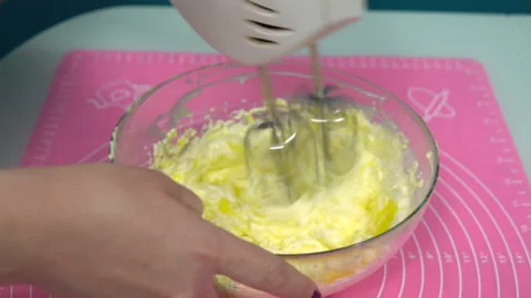 Adding eggs to the cream and whipping with a mixer close-up. Making Valentine's Stock Footage 146869675