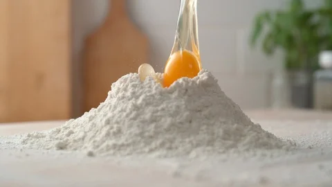 Adding eggs into a pile of flour. Slow Motion. Stock Footage 121492960