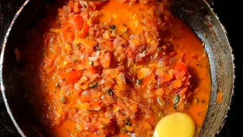 Adding eggs on top of frying onions and tomatoes. Video stock 201510319