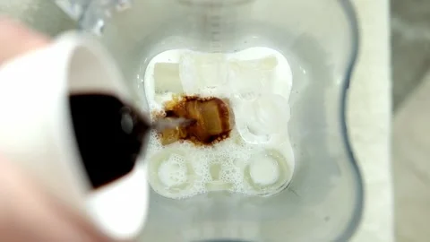 Adding espresso coffee to ice cubes and milk in blender, making iced coffee Stock Footage 307273923