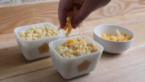 Adding extra cheddar cheese to the top of macaroni and cheese. Stock Footage 143892136