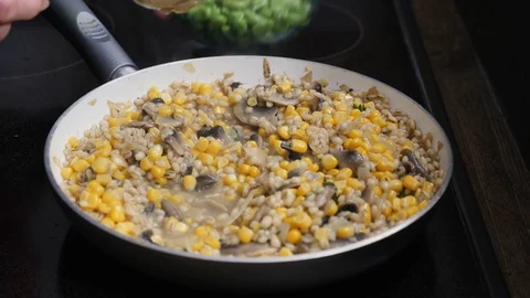 Adding fava beans to barley risotto with mushrooms and corn Stock Footage 88110991