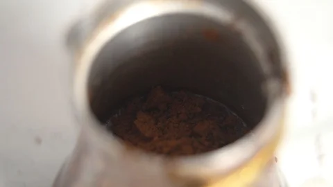 Adding finely ground coffee into copper Cezve to make Turkish coffee closeup Stock Footage 123670593