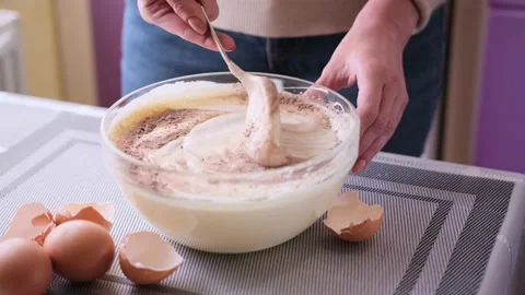 Adding flour and cocoa to beaten eggs - making dough for baking Stock Footage 185918712